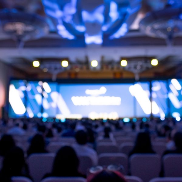 Blurred,Image,Of,Stage,With,Rear,View,Of,Audience,In